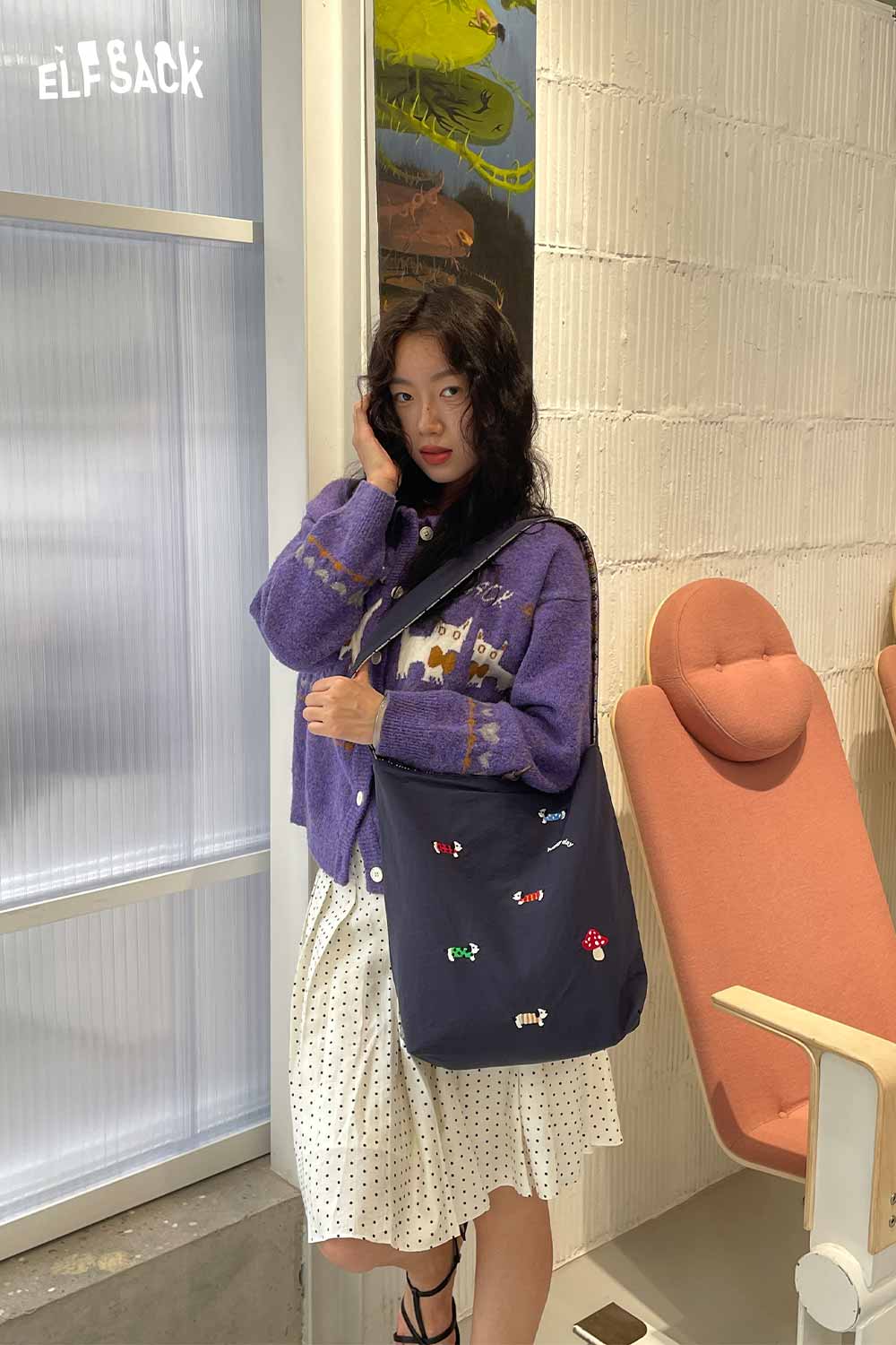 Stylish woman wearing a sweater with a multi color checkered shoulder bag, perfect for casual outings