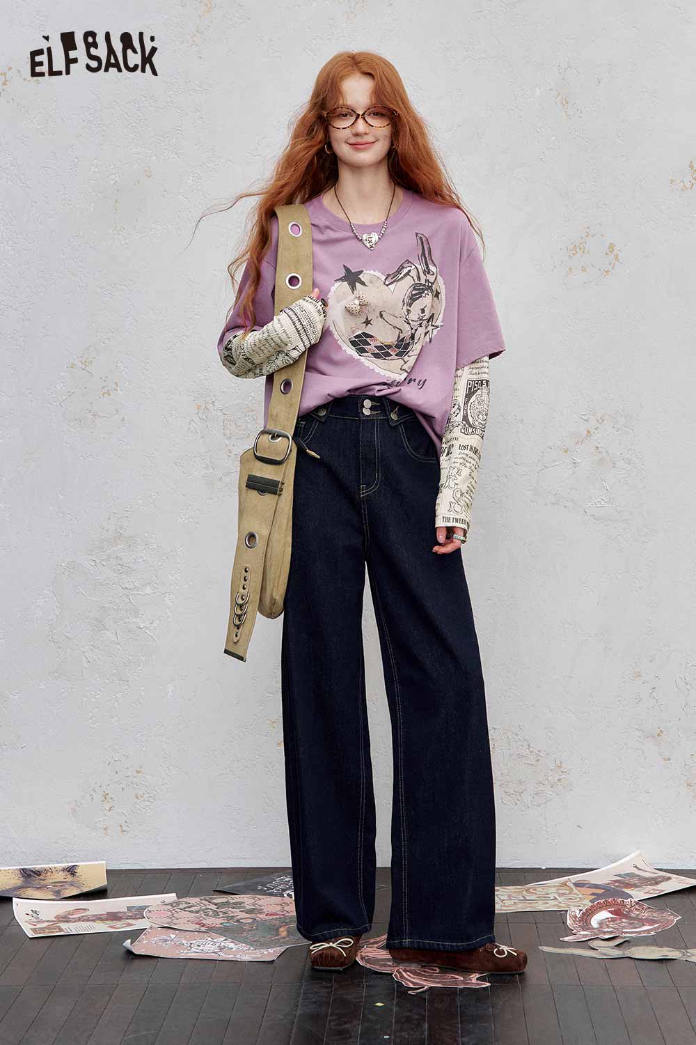 ELFSACK newsprint graphic drop shoulder tee in purple featuring a unique cat design, paired with wide-leg jeans.