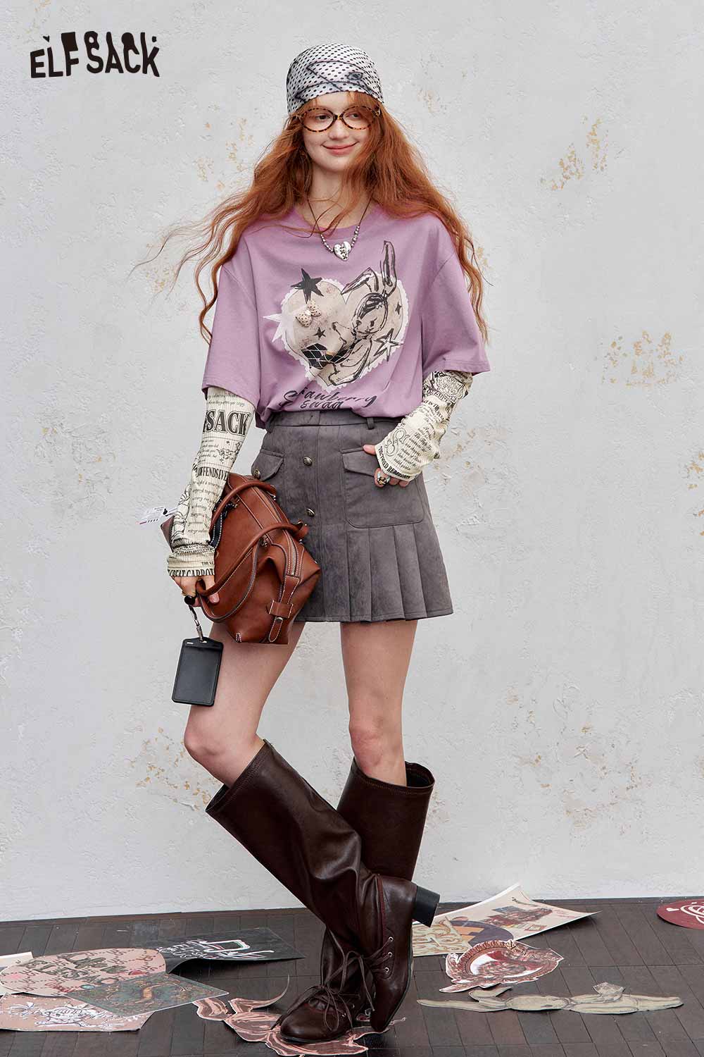 ELFSACK newsprint graphic drop shoulder tee in lavender paired with a pleated skirt and knee-high boots