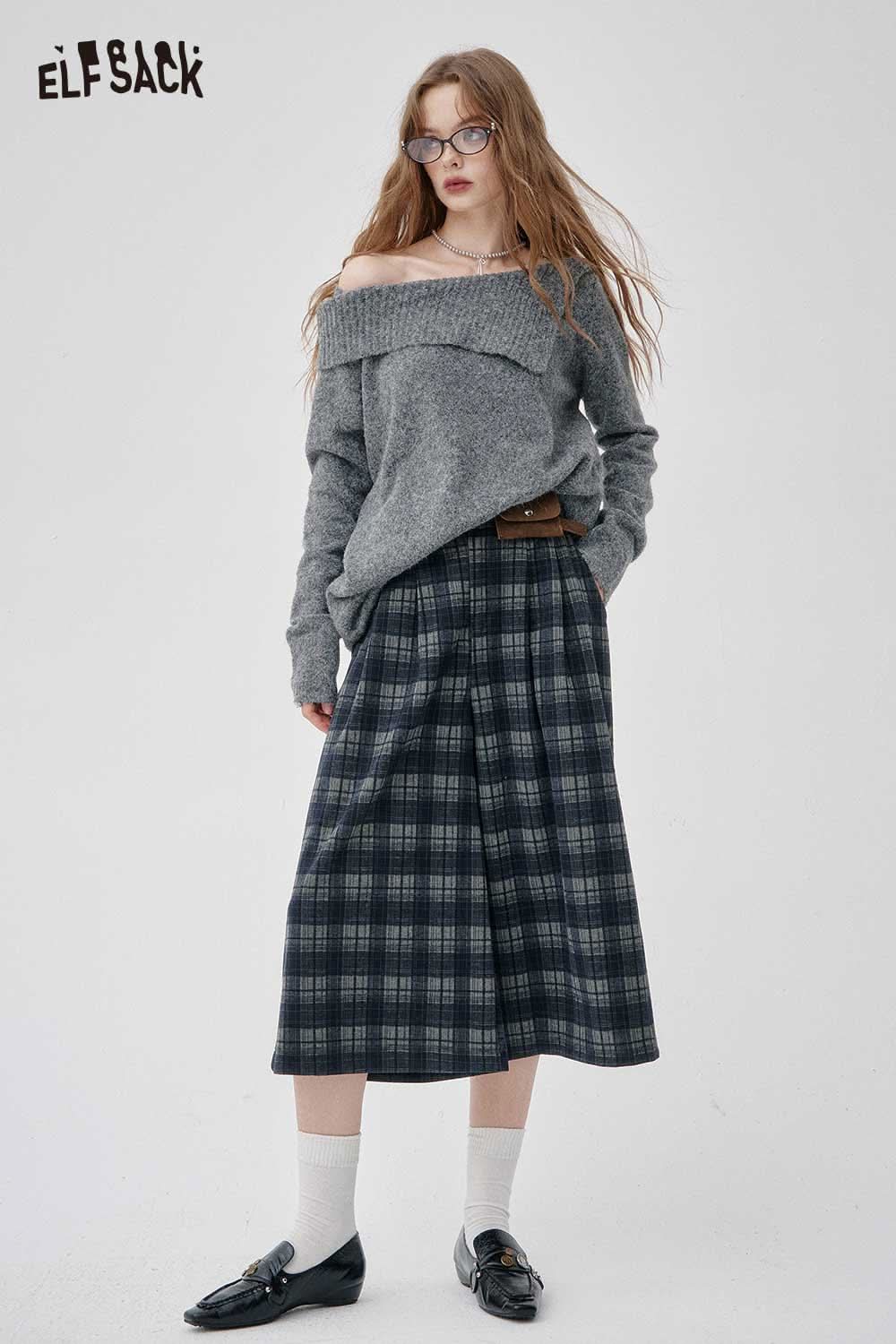 Model wearing off-the-shoulder oversized knit sweater paired with plaid pants for a stylish look