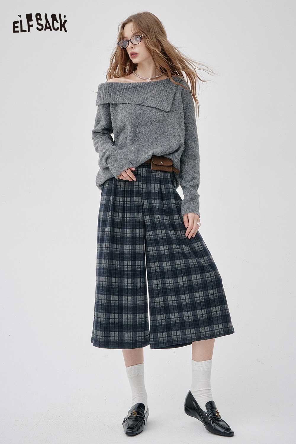 Woman wearing plaid wide-leg pants paired with an off-the-shoulder oversized knit sweater in gray