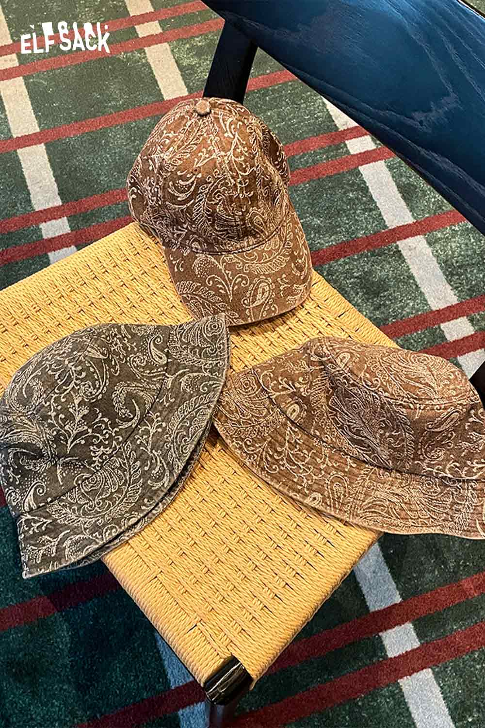 Three ELFSACK paisley print bucket hats for women displayed on a wicker table