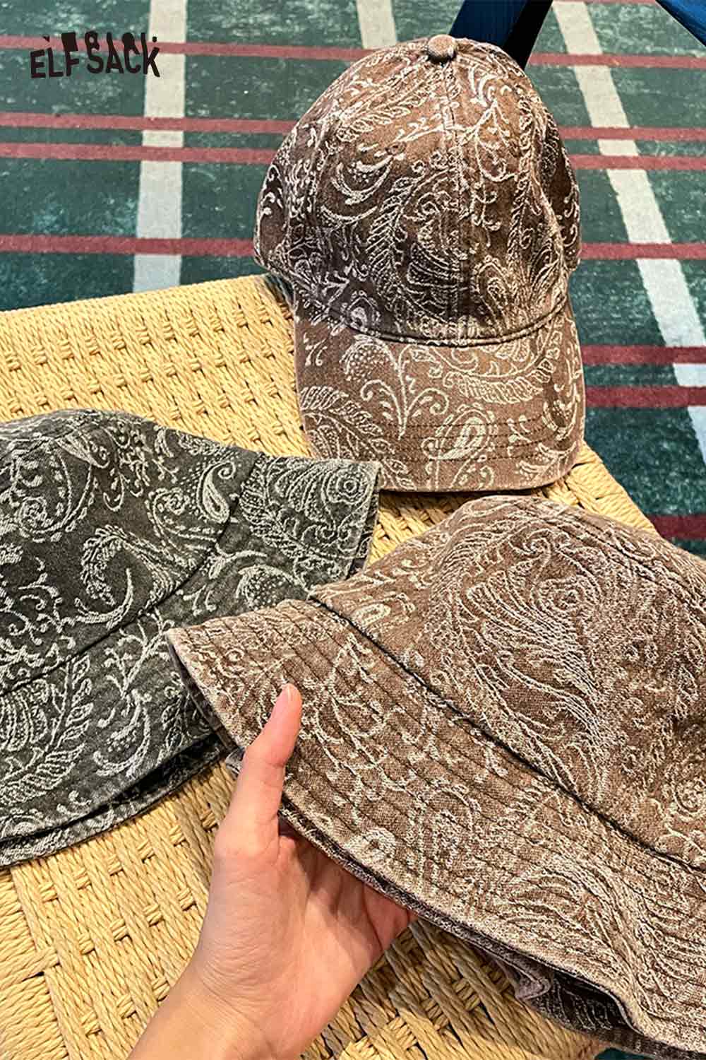 ELFSACK paisley print bucket hat for women in brown and gray displayed on a woven surface
