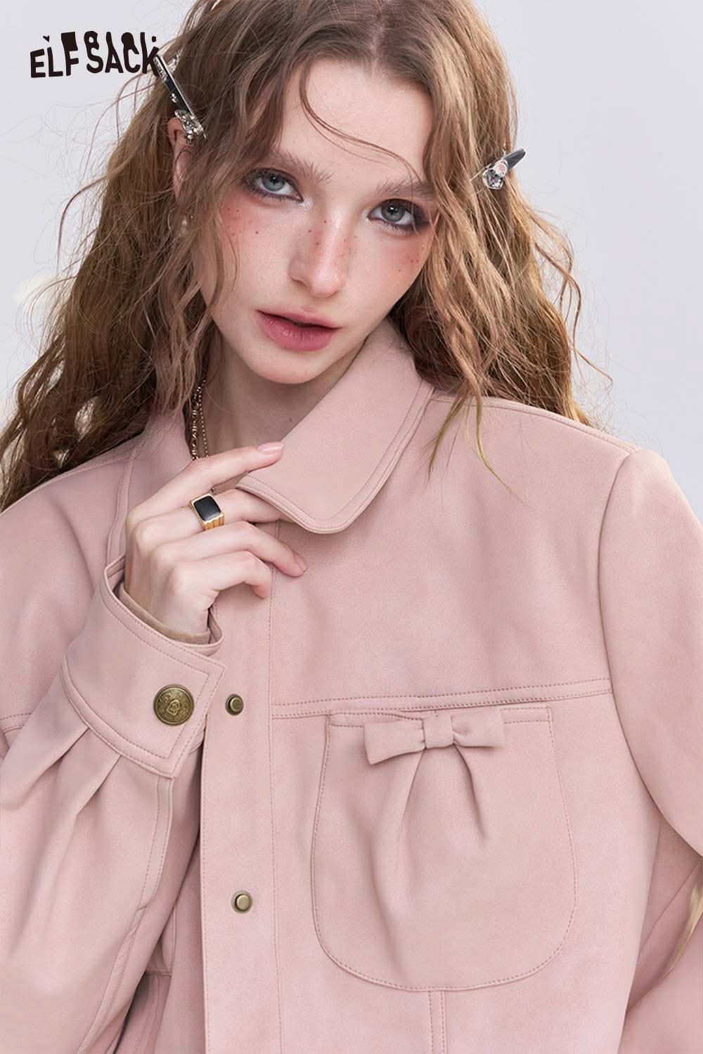 Stylish woman wearing a pink faux leather motocross jacket with a bow detail on the pocket