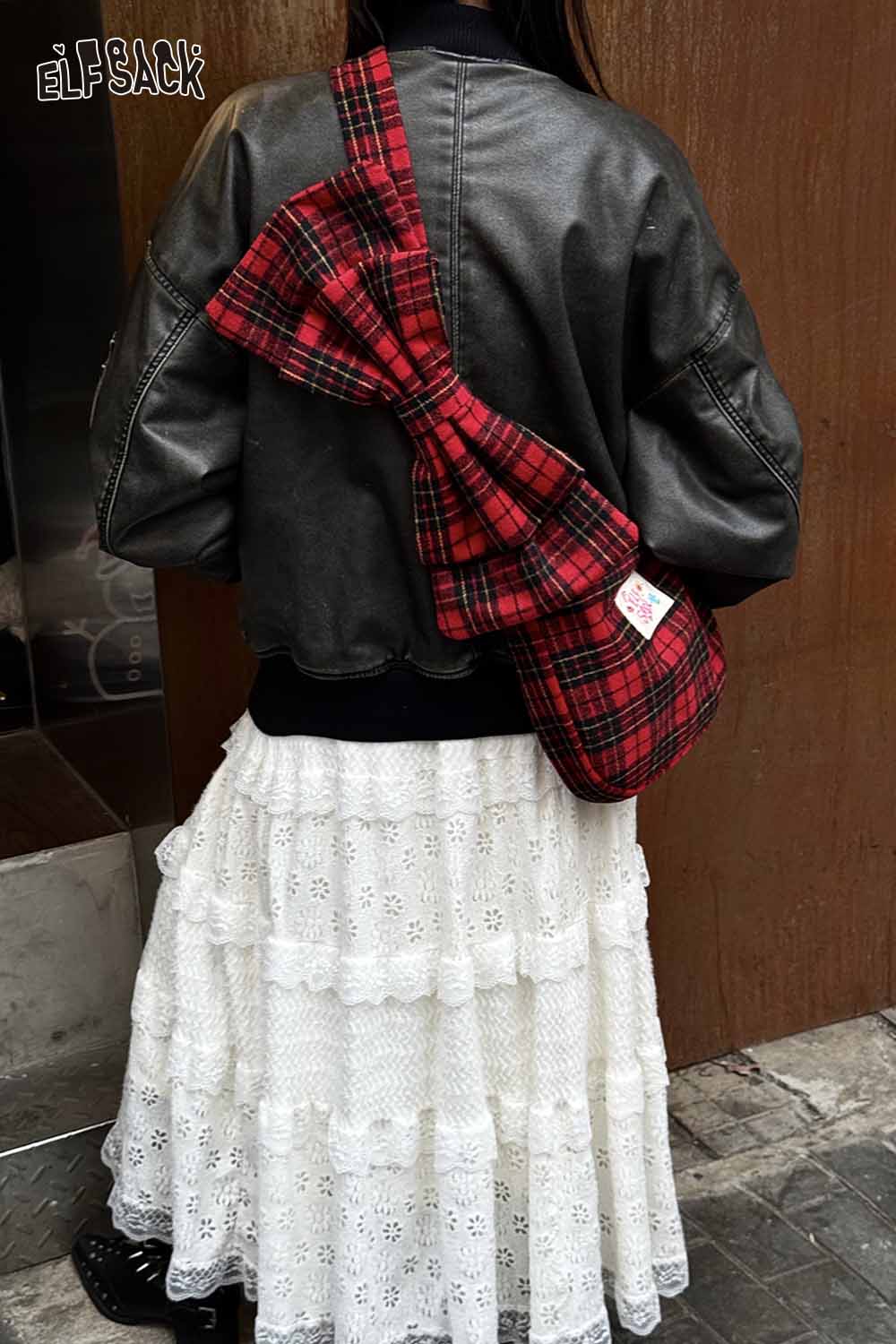 Stylish ELFSACK plaid bow crossbody bag in red and black worn casually over a black jacket