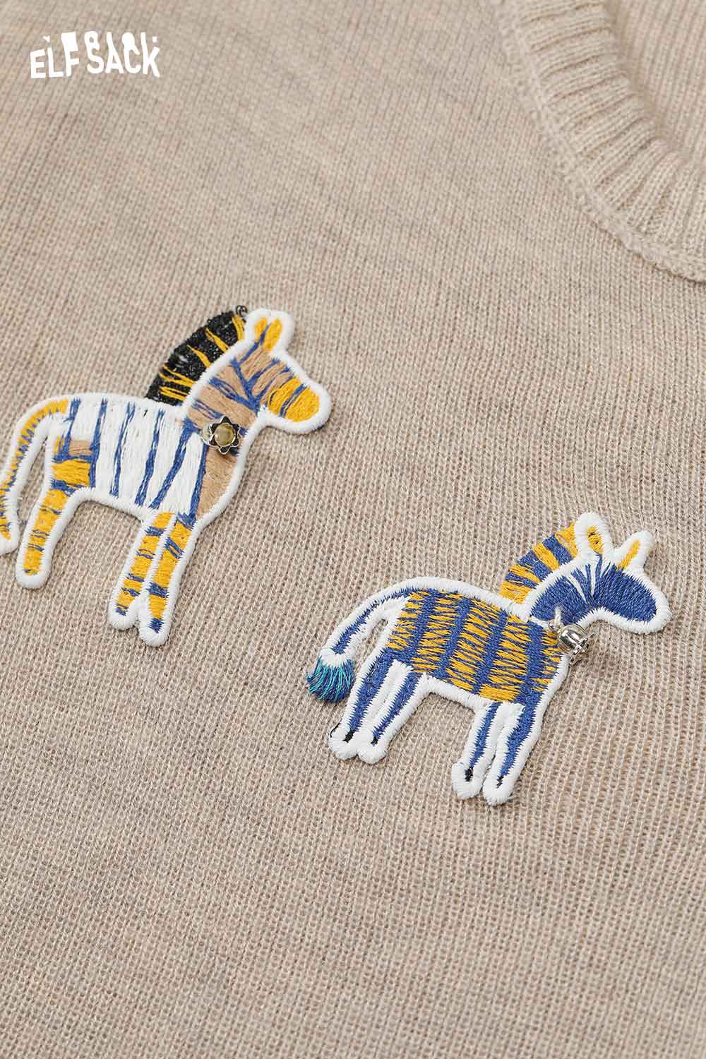 ELFSACK playful animal motif cardigan featuring colorful zebra appliques on a beige background
