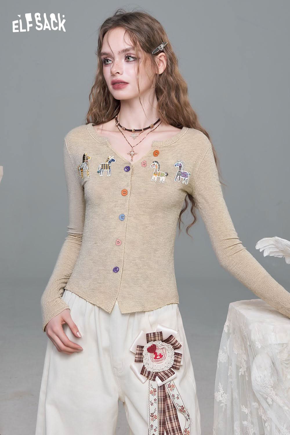 ELFSACK playful animal motif cardigan with colorful buttons and whimsical designs on a beige background