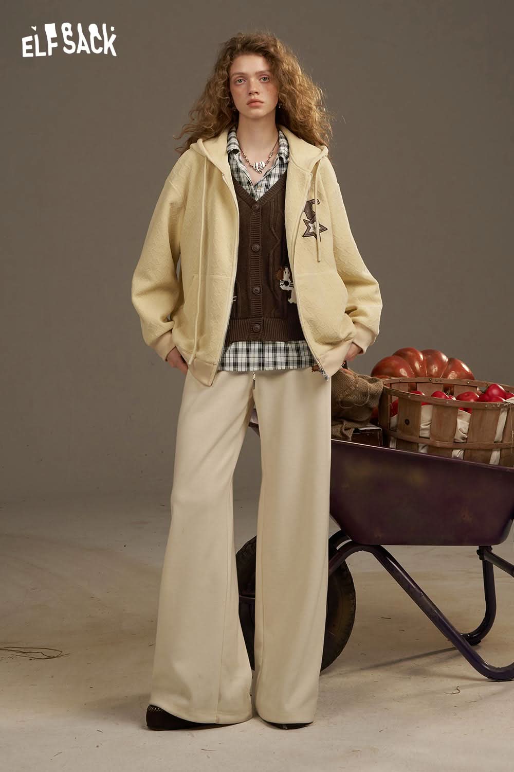 Casual outfit featuring a playful embroidered knit top paired with a beige hoodie and wide-leg trousers