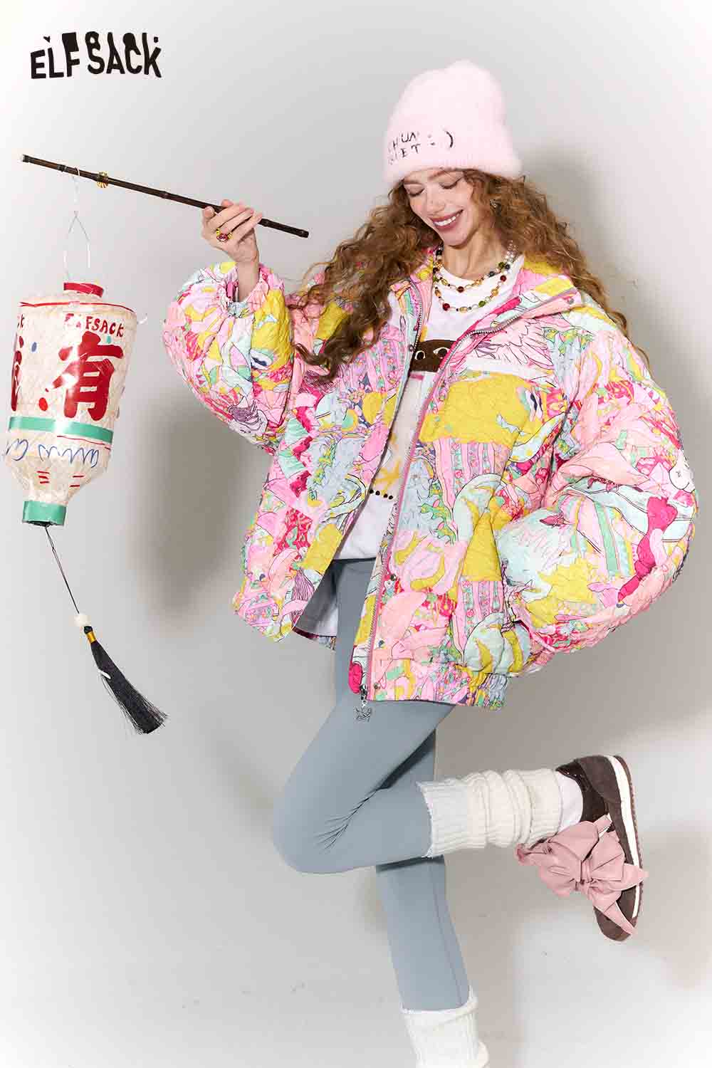 ELFSACK playful graphic bomber jacket for women in colorful patterns, paired with light blue pants and a pink beanie