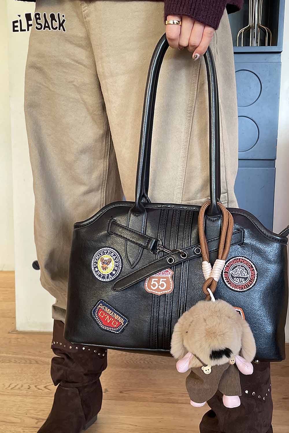 ELFSACK plush animal keychain attached to a stylish handbag with various patches