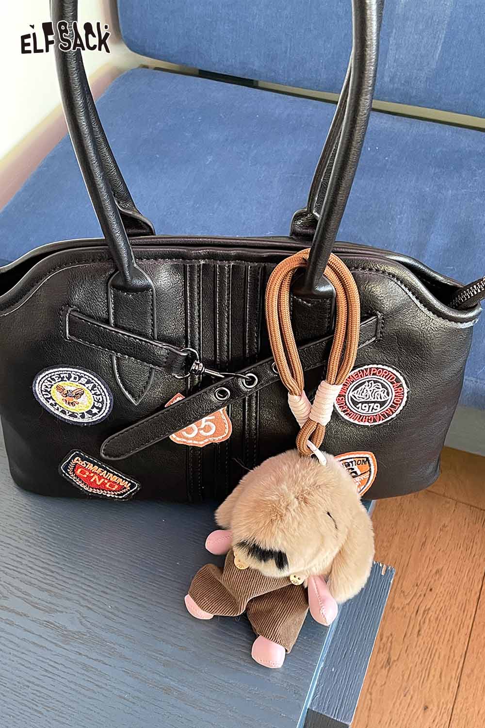 Black handbag with patches and a plush animal keychain attached for a stylish accessory look