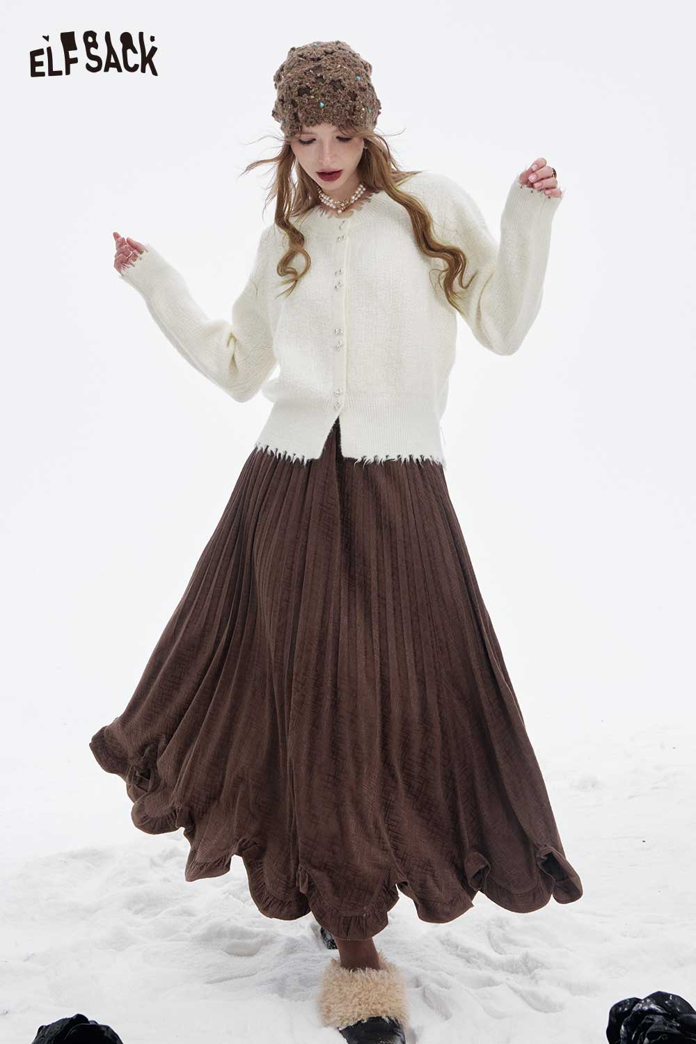 ELFSACK preppy fringe sweater for women paired with a stylish brown pleated skirt in a snowy setting