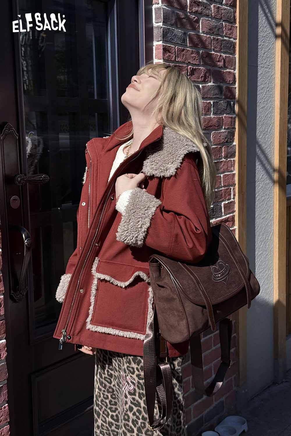 Stylish woman wearing a red ELFSACK jacket with preppy suede backpack for women on her shoulder