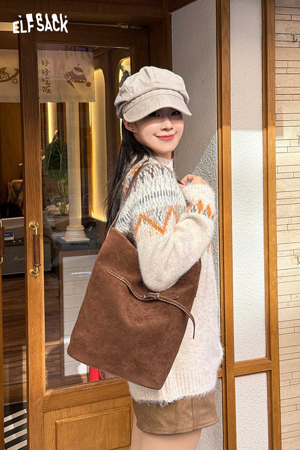 Trendy ELFSACK PU leather bucket bag for women in brown, styled with a cozy sweater and cap