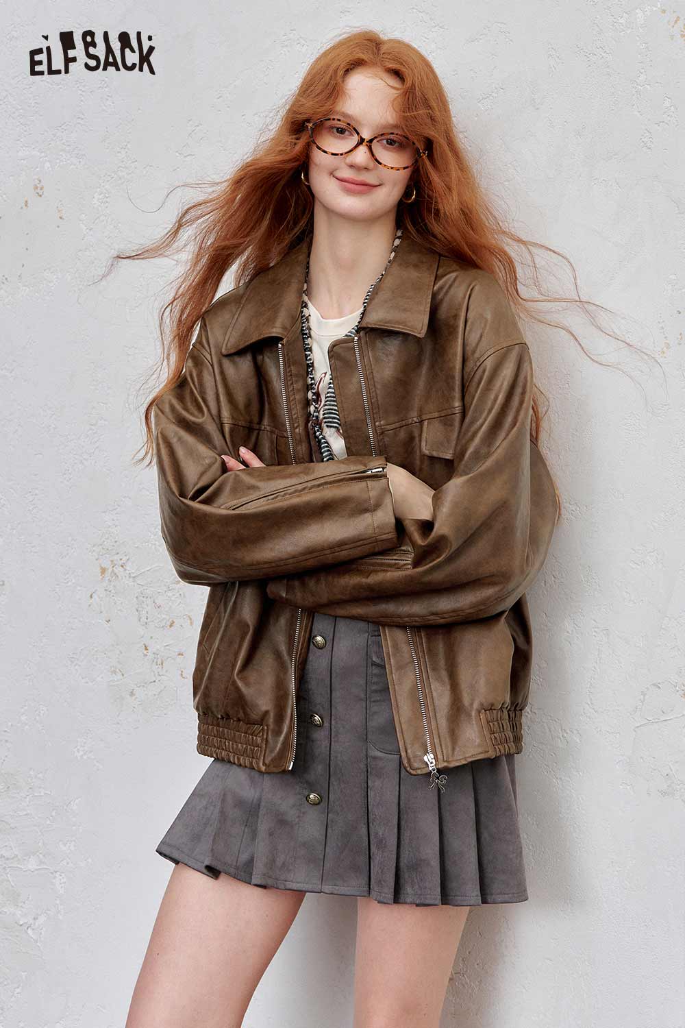 Brown ELFSACK PU leather motocross jacket for women styled with a pleated skirt and accessories