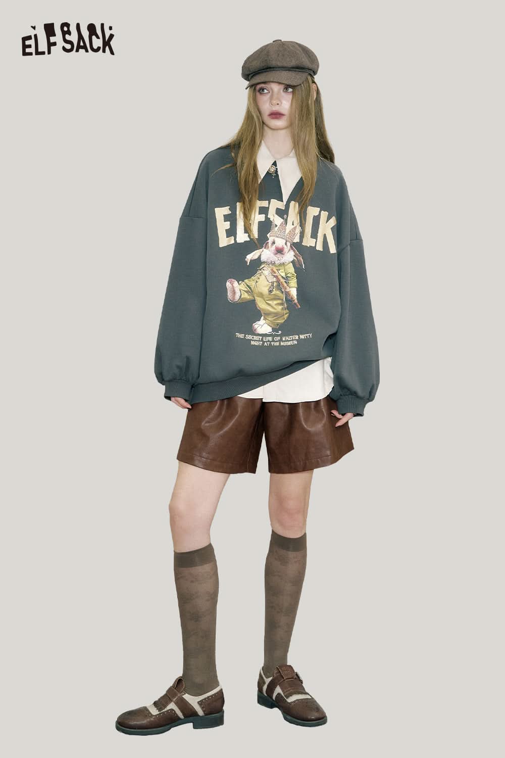 Model wearing ELFSACK PU leather pleated shorts paired with an oversized sweatshirt and cap