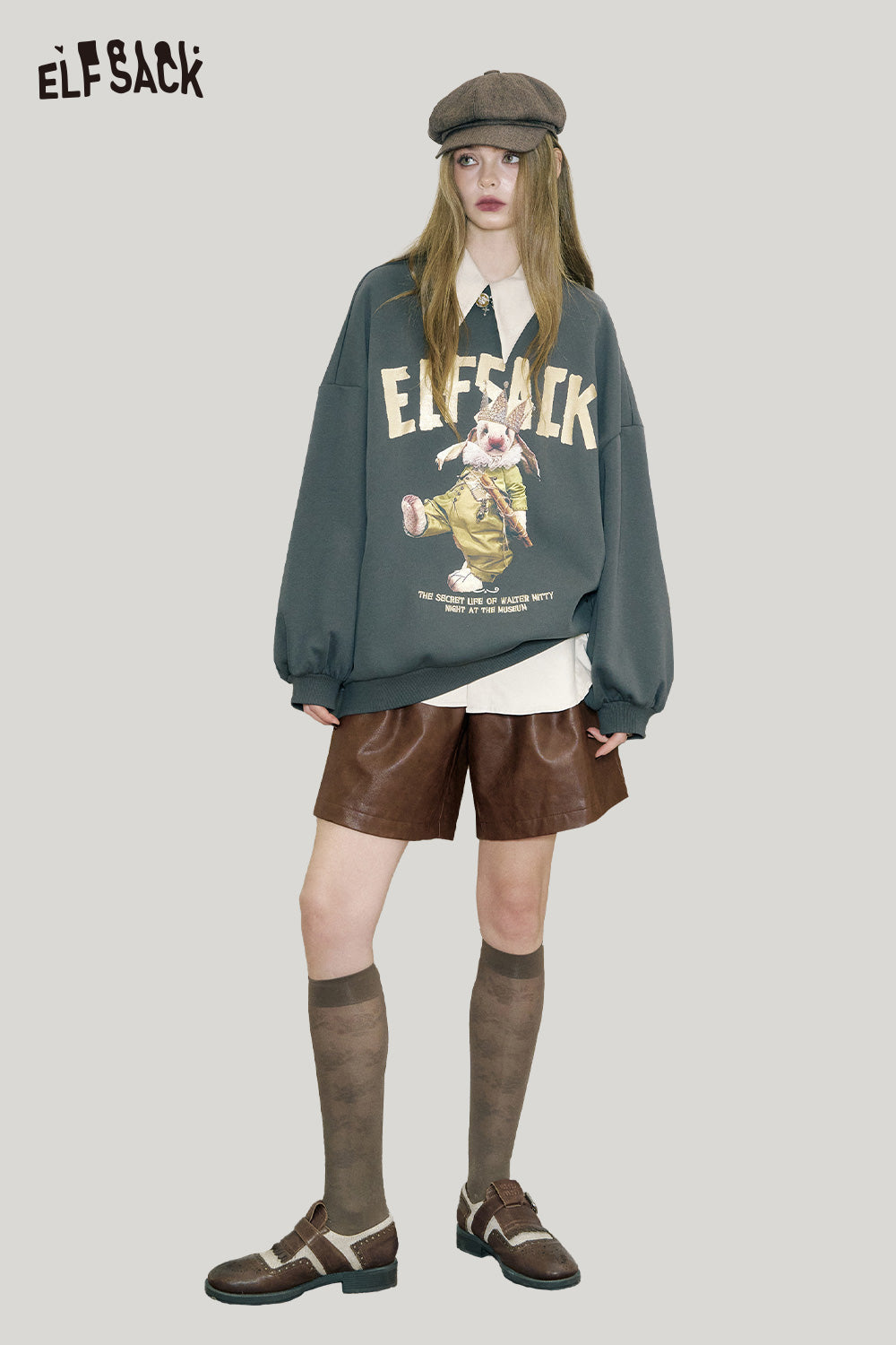 Model wearing ELFSACK PU leather pleated shorts paired with an oversized sweatshirt and cap