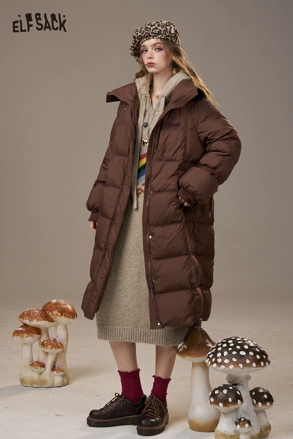 ELFSACK model wearing a cozy rainbow cartoon sweater dress paired with a chic brown puffer coat