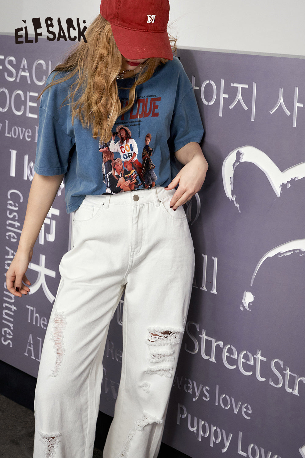 ELFSACK Retro Graphic blue T-shirt worn with white ripped jeans and red cap