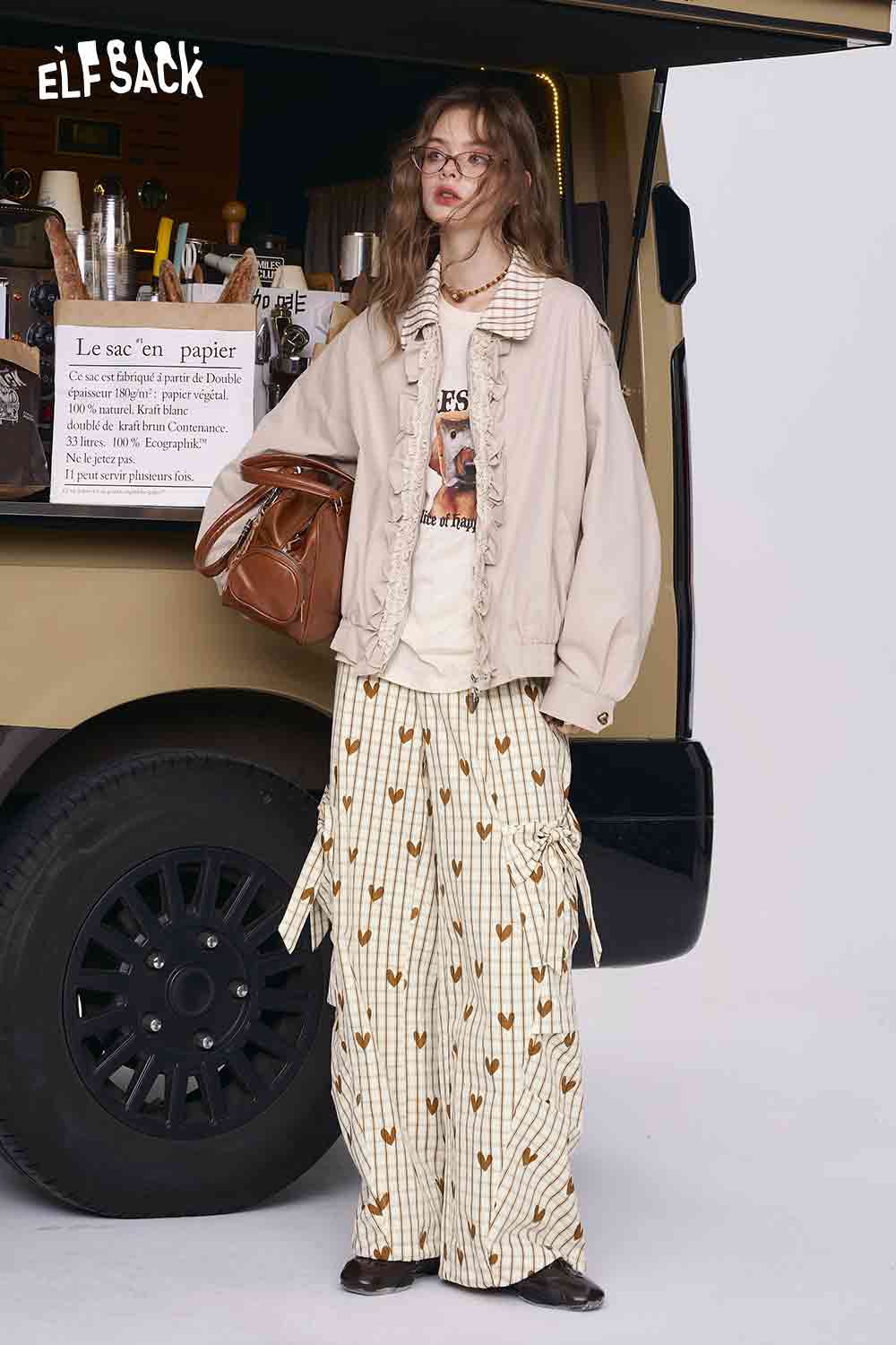 ELFSACK model wearing heart plaid wide-leg pants cream striped hearts with side ties paired with beige jacket