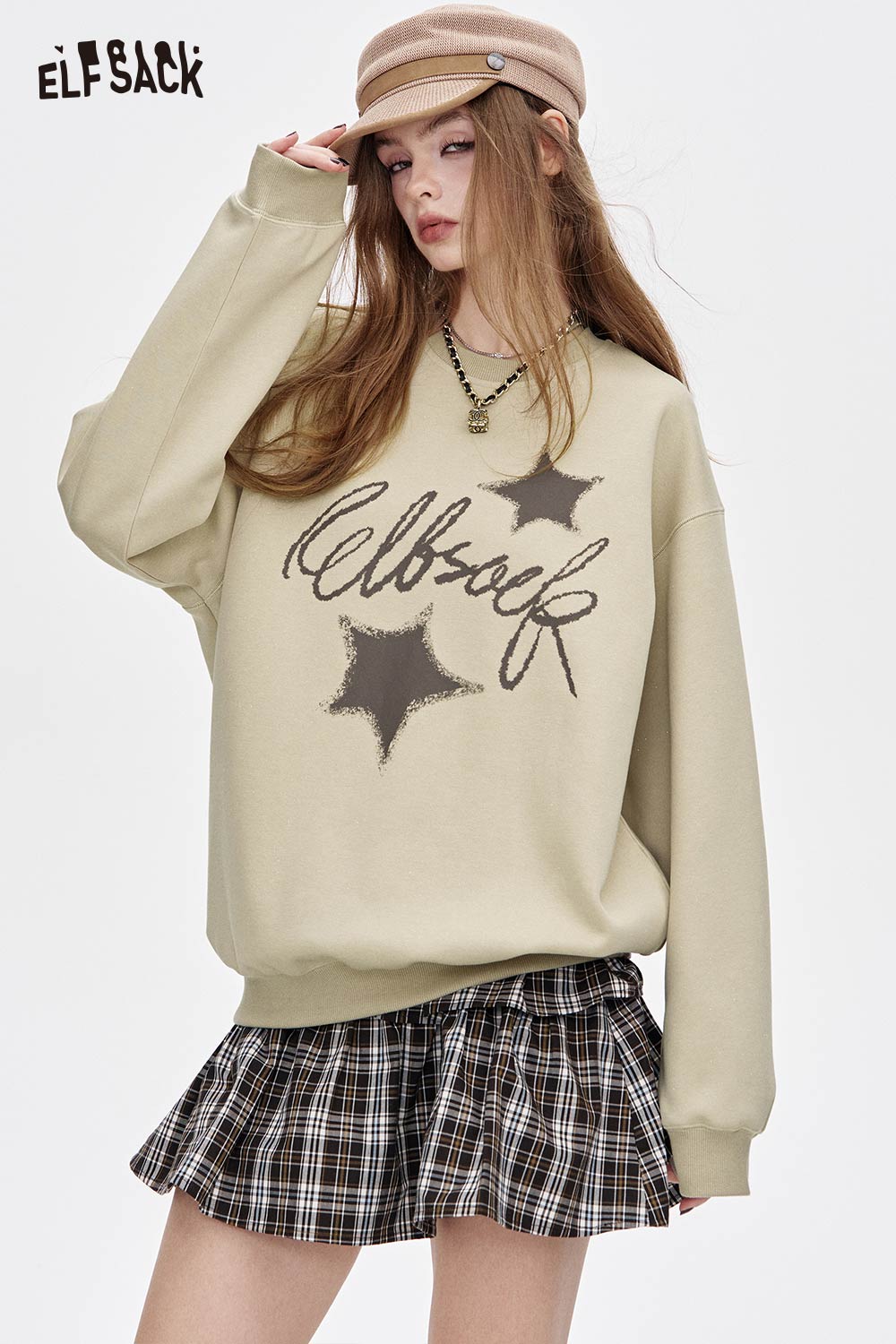 ELFSACK oversized graphic star sweatshirt in beige, featuring star graphics and relaxed fit, paired with a plaid skirt.
