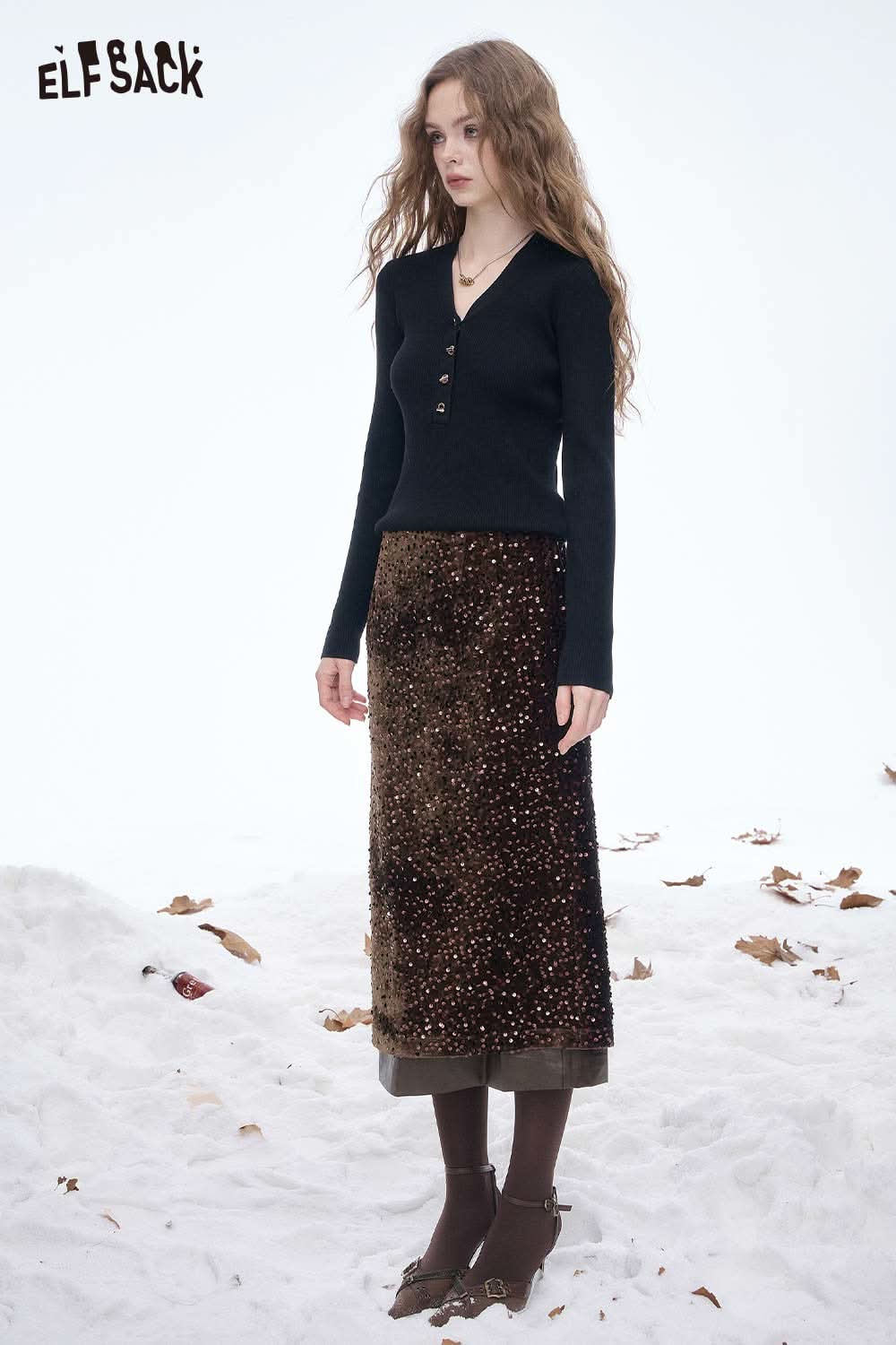 Model wearing an ELFSACK sequin faux leather long skirt in a snowy setting, styled with a fitted black top.