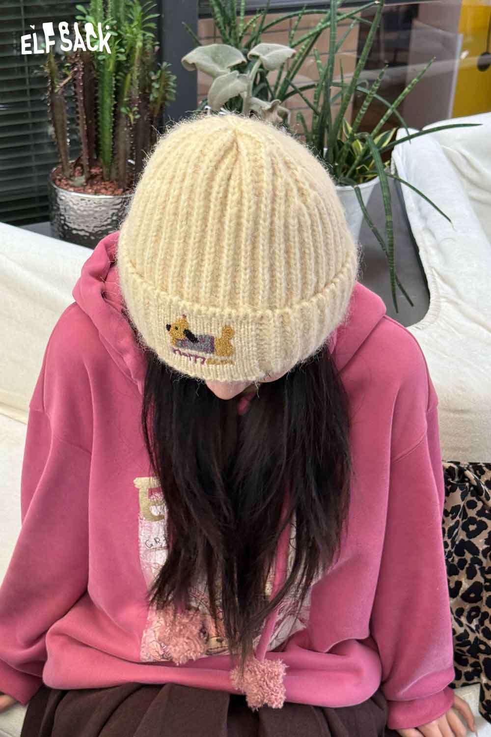 ELFSACK soft dog embroidered hat in cream color, worn with a pink hoodie for a cozy look