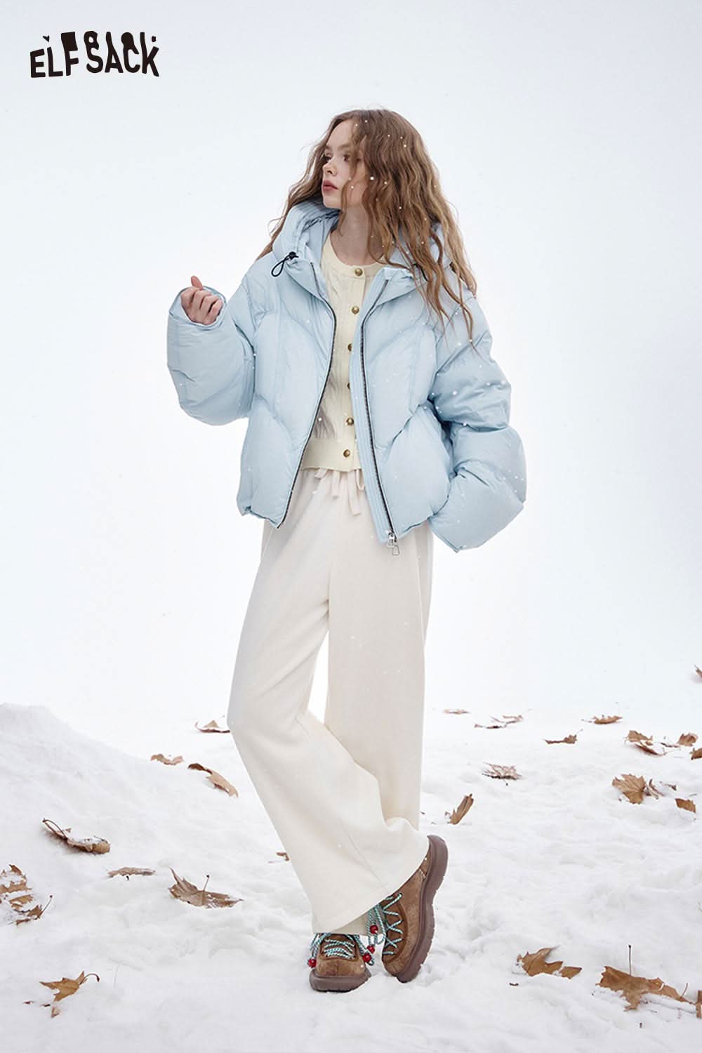 ELFSACK soft embroidered knit sweater paired with a stylish puffer jacket and cream pants in a winter setting