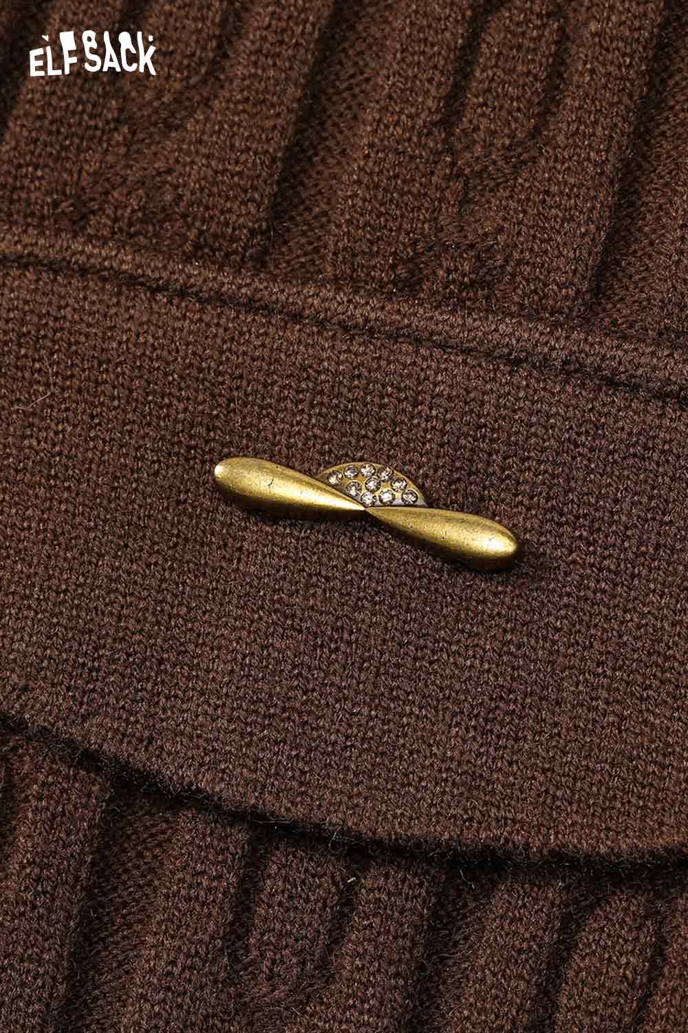 Close-up of ELFSACK soft flared tea dress with stylish gold brooch detail on textured fabric