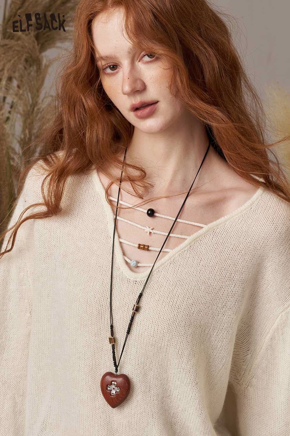 ELFSACK soft knit lace-up sweater in cream color, styled with a unique necklace and a relaxed fit