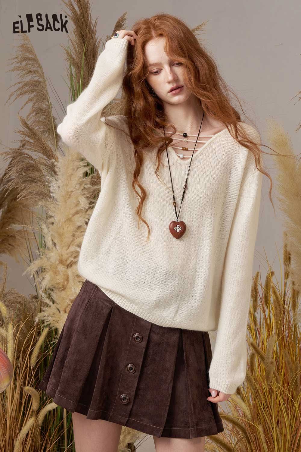 ELFSACK soft knit lace-up sweater in cream, styled with a brown skirt and heart-shaped pendant necklace