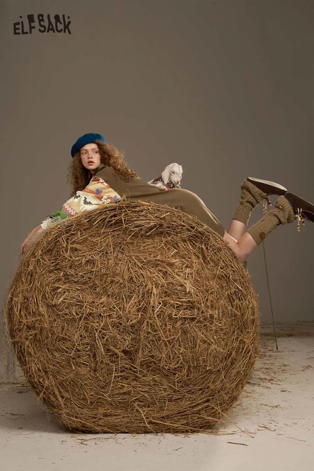 ELFSACK soft patchwork sleeve dress modeled casually with a playful pose on a hay bale