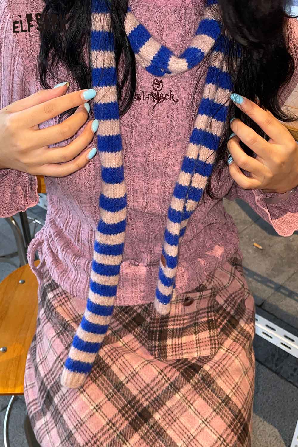 Close-up of a soft striped scarf for women in blue and beige, styled with a cozy outfit