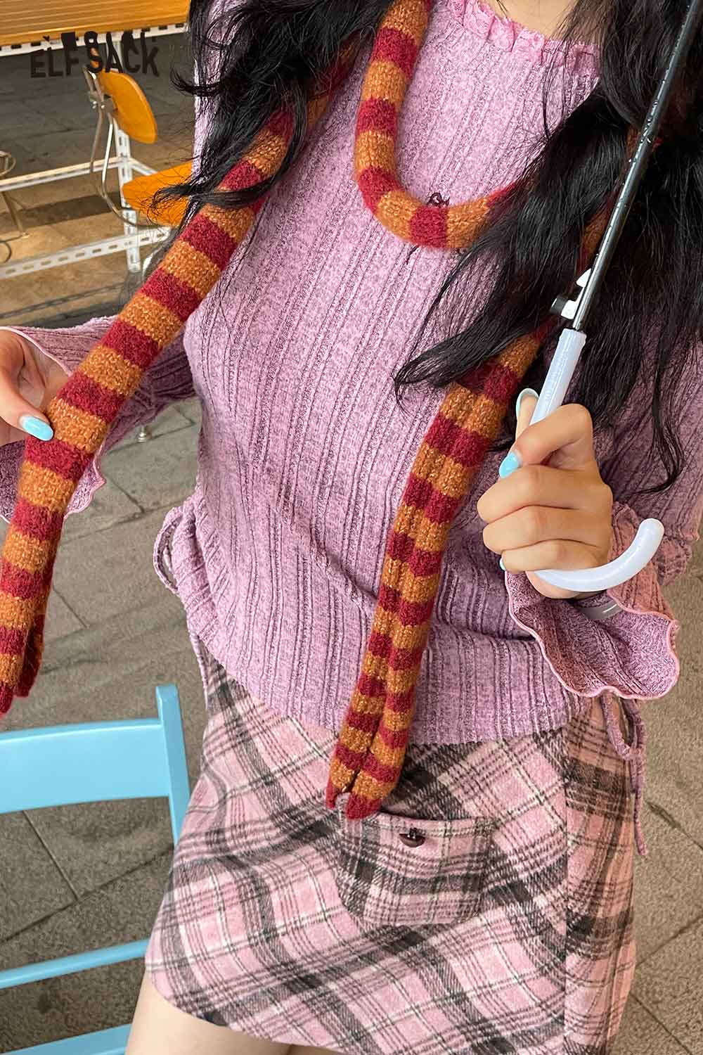 Trendy soft striped scarf for women styled with a pink top and plaid skirt, perfect for casual outings