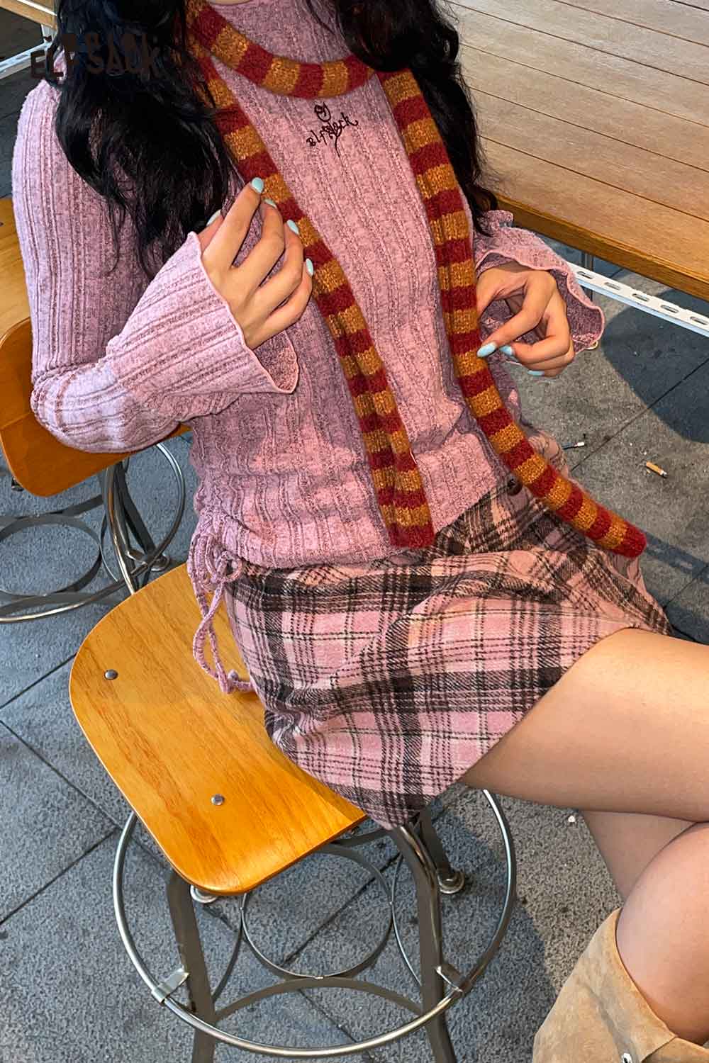 ELFSACK soft striped scarf for women paired with a pink sweater and plaid skirt in a cozy cafe setting
