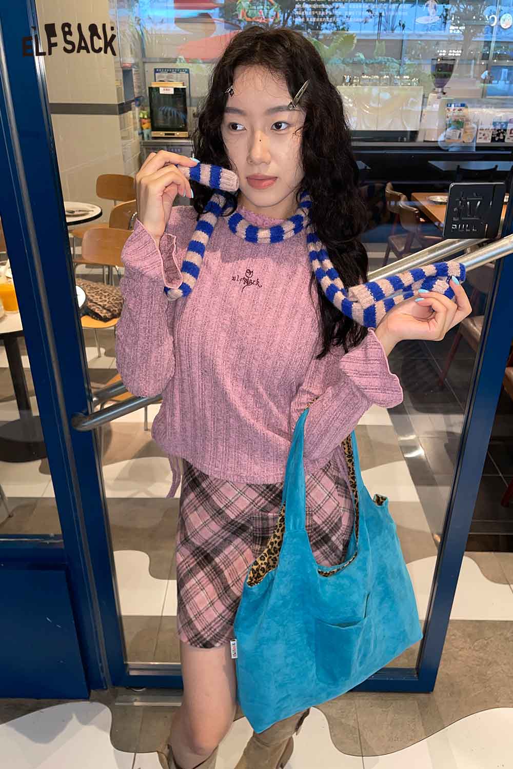 ELFSACK soft striped scarf for women styled with a pink sweater and plaid skirt in a cafe setting