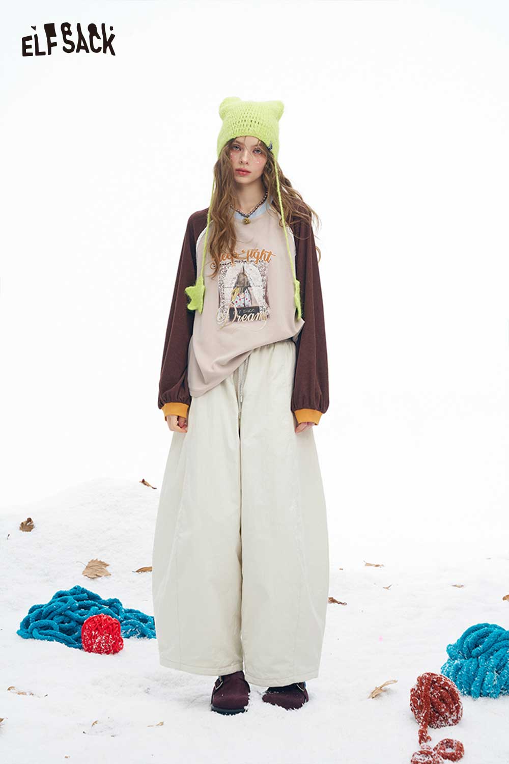 ELFSACK soft wide leg pants for women in cream color, paired with a graphic hoodie and playful accessories