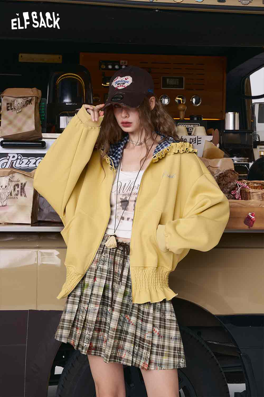 ELFSACK model wearing a pleated college style plaid mini skirt in green tones with casual street styling