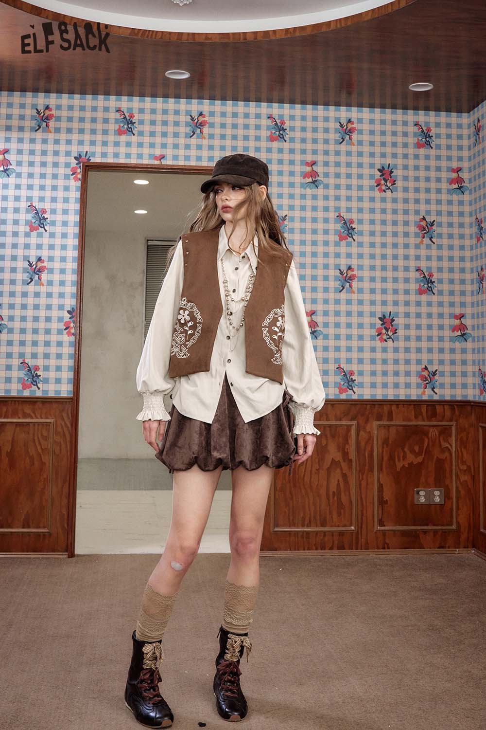ELFSACK suede bloomer mini skirt styled with a vintage blouse and accessories in a patterned room