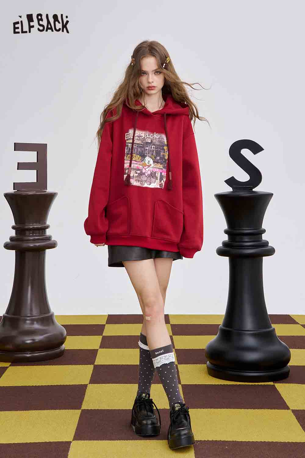 Model wearing a red hoodie with graphic design, paired with teddy bear hair clips for a stylish look