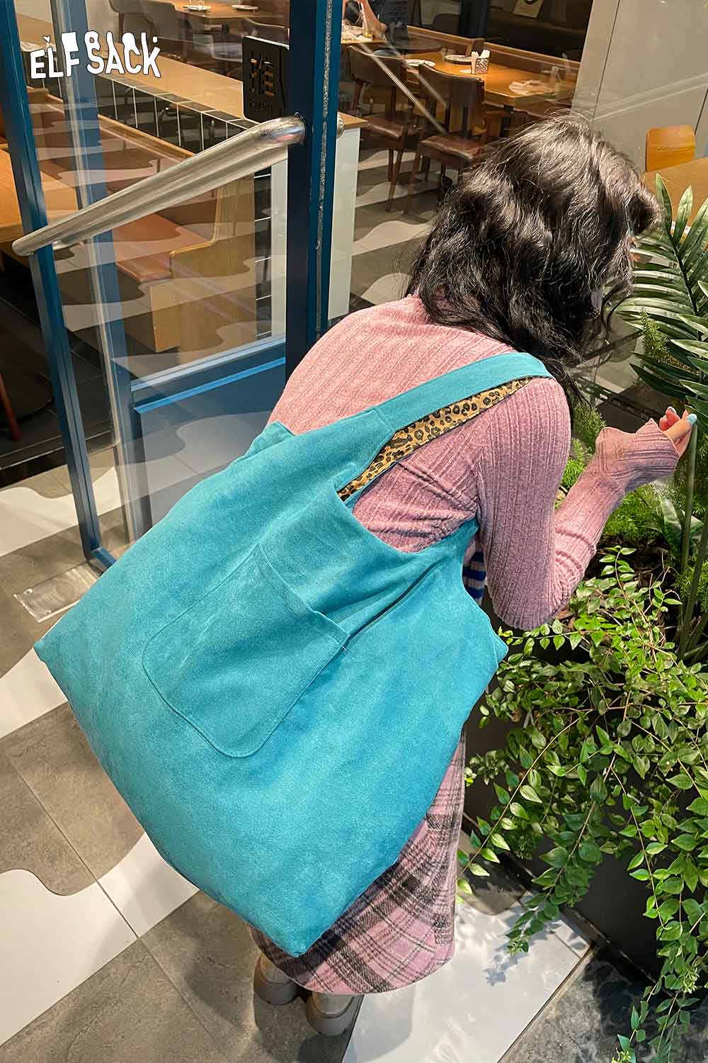 Woman holding a textured oversized hobo bag by ELFSACK in bright blue with a stylish design