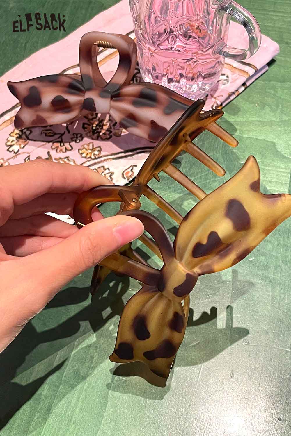 ELFSACK tortoiseshell bow hair claw in hand, perfect for stylish hair styling and accessories