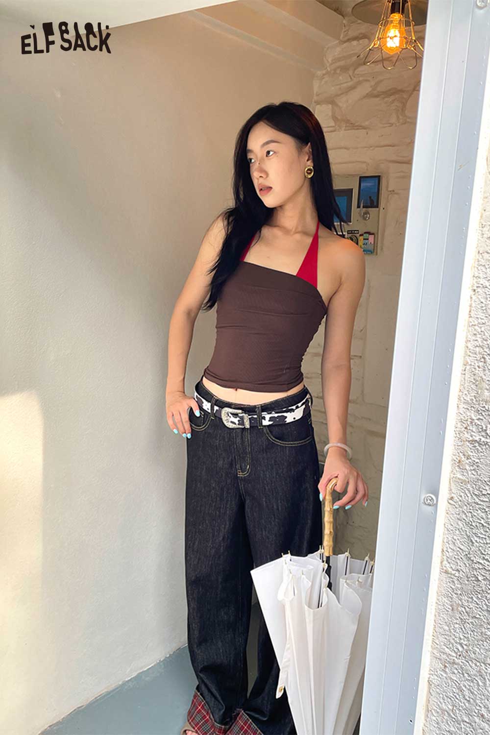 Stylish woman wearing a vegan leather cowhide pattern belt with casual jeans and a halter top