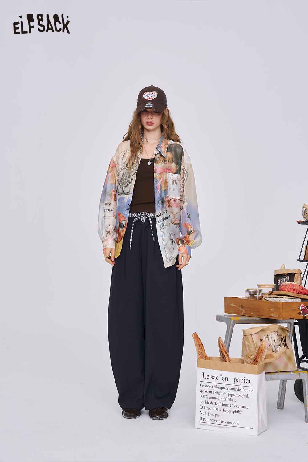 ELFSACK women all over print long sleeve shirt styled over black jumpsuit with baseball cap