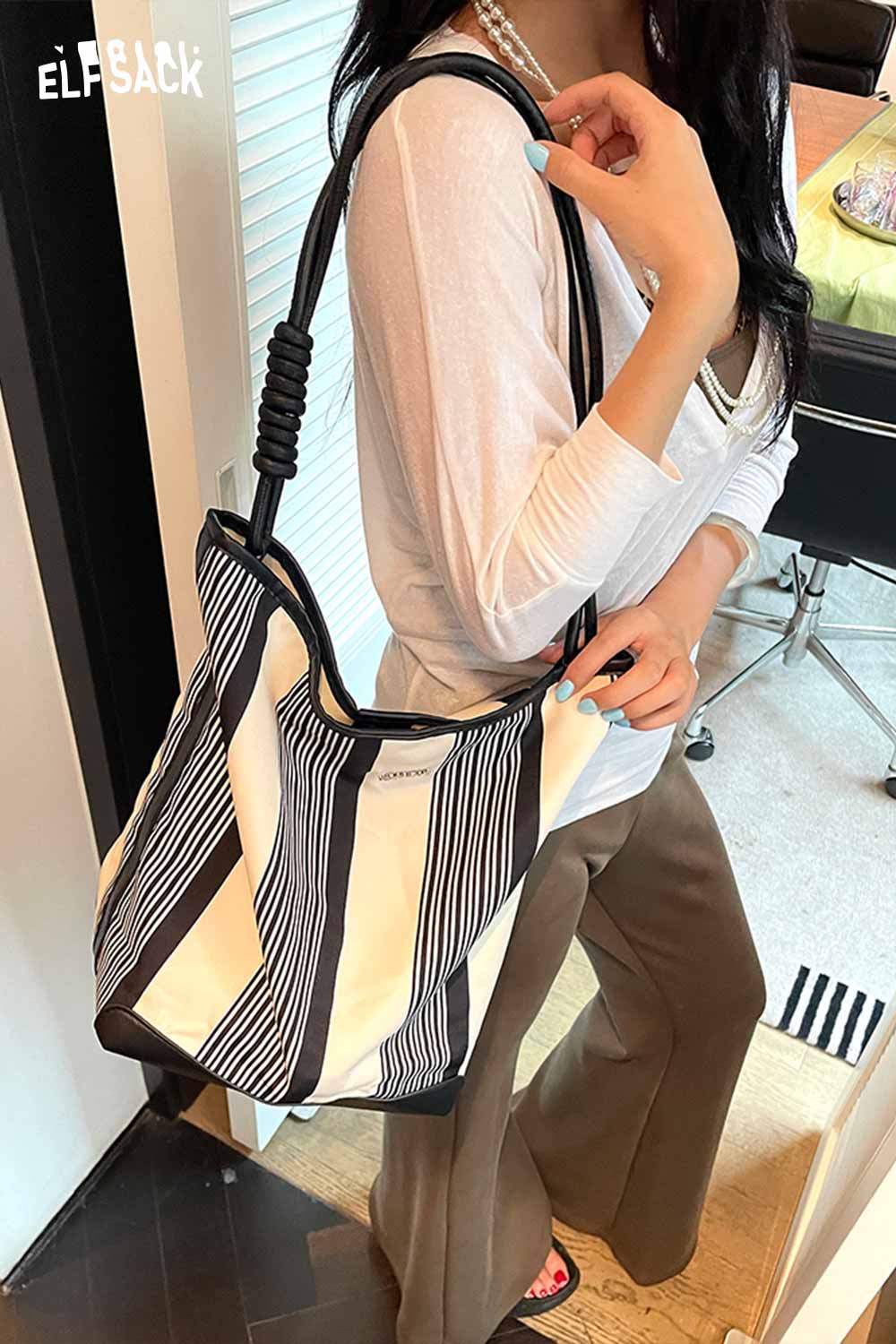 Woman carrying a contrast stripe canvas tote bag with stylish black and white stripes.