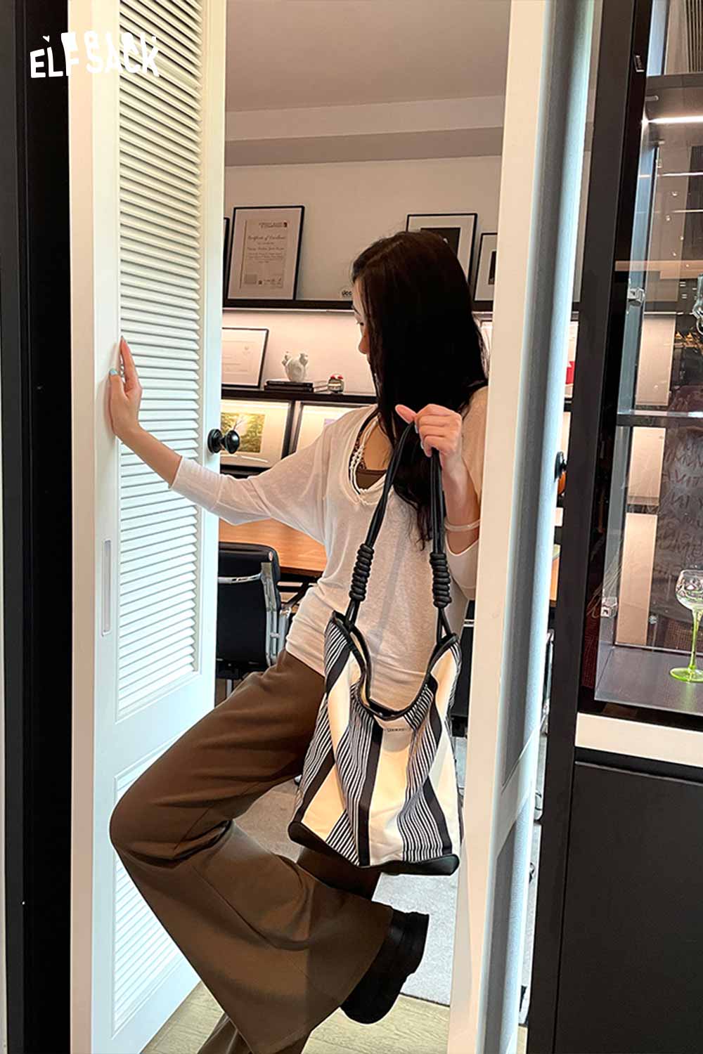 Stylish woman posing with a contrast stripe canvas tote bag in a modern interior setting