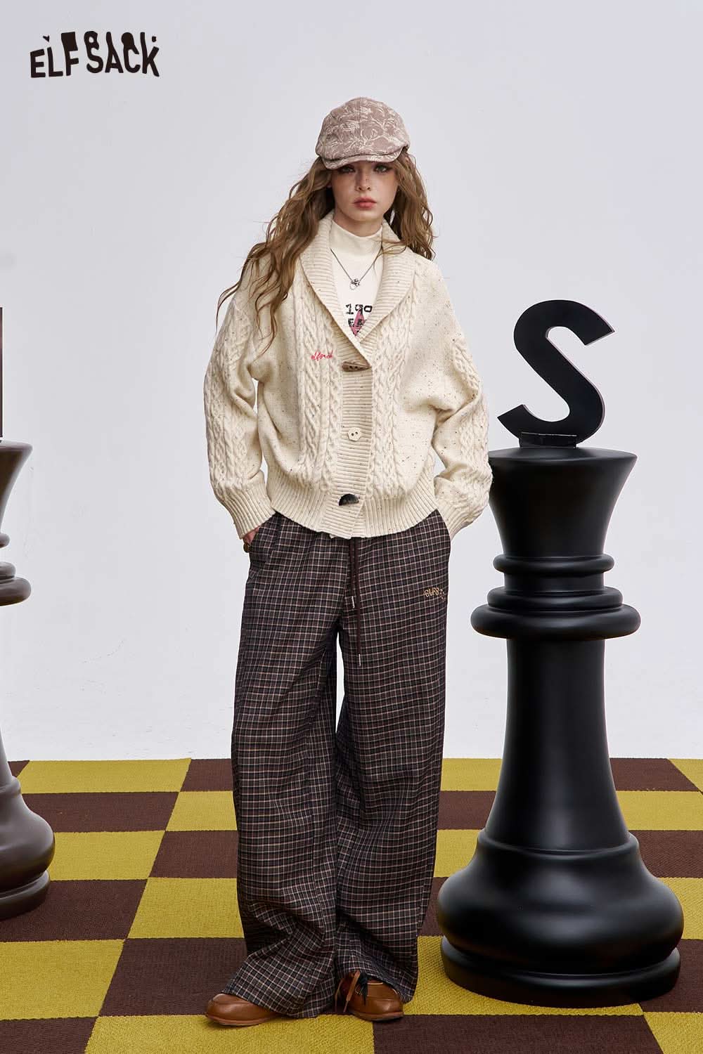 ELFSACK irregular button knit sweater in cream, styled with wide plaid trousers and a cap
