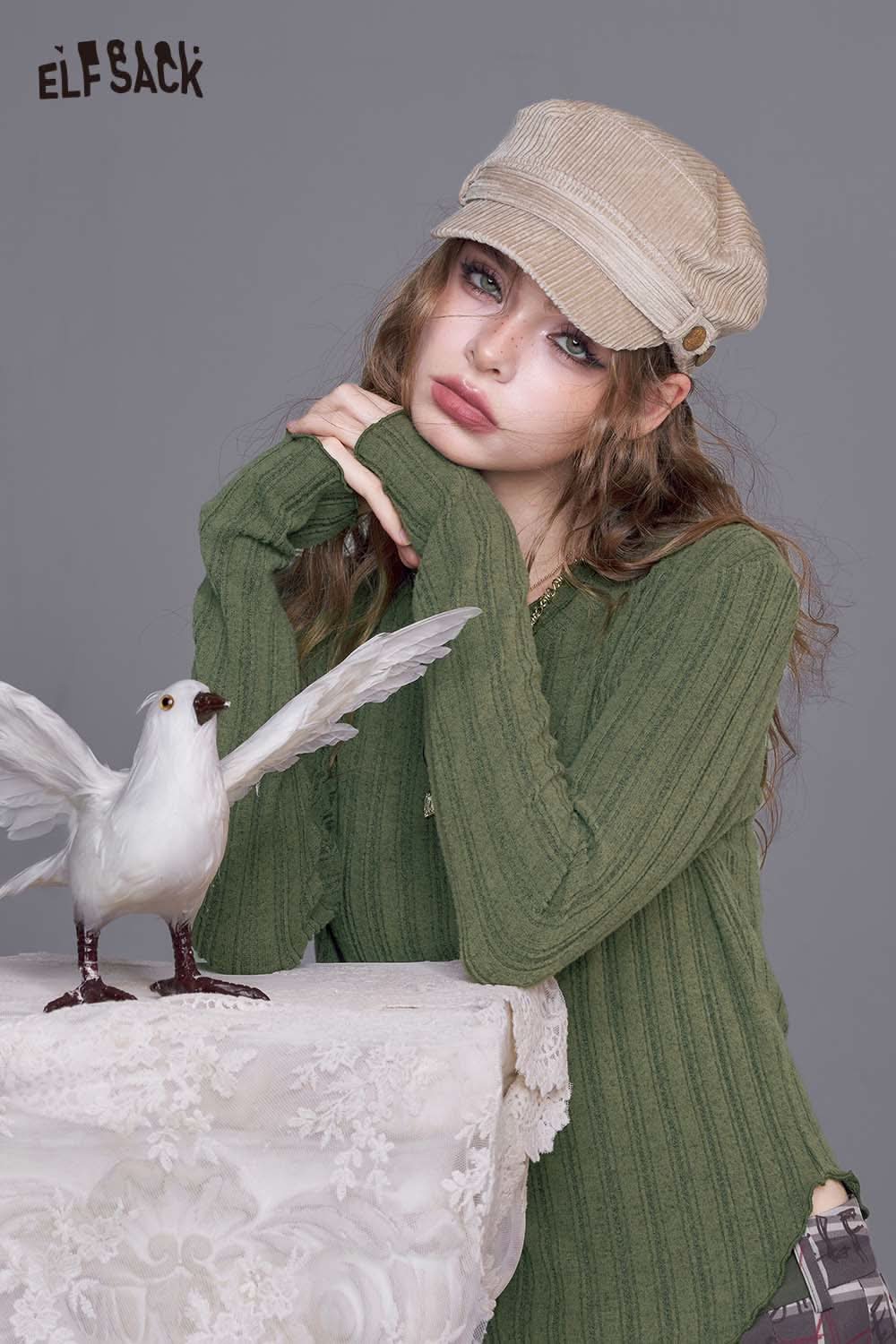 ELFSACK women's stretch knit top in green with ribbed texture, styled with a cap and posing with a bird