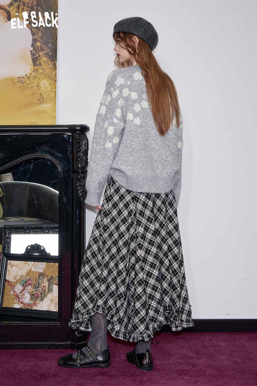 Woman wearing a wool blend checkered skirt paired with a cozy sweater and hat in a stylish setting