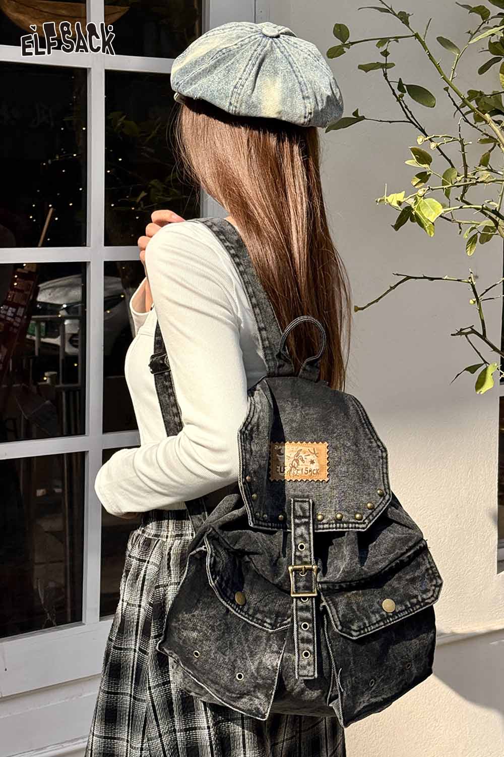 ELFSACK vintage black denim backpack featured on a model wearing a stylish outfit and cap